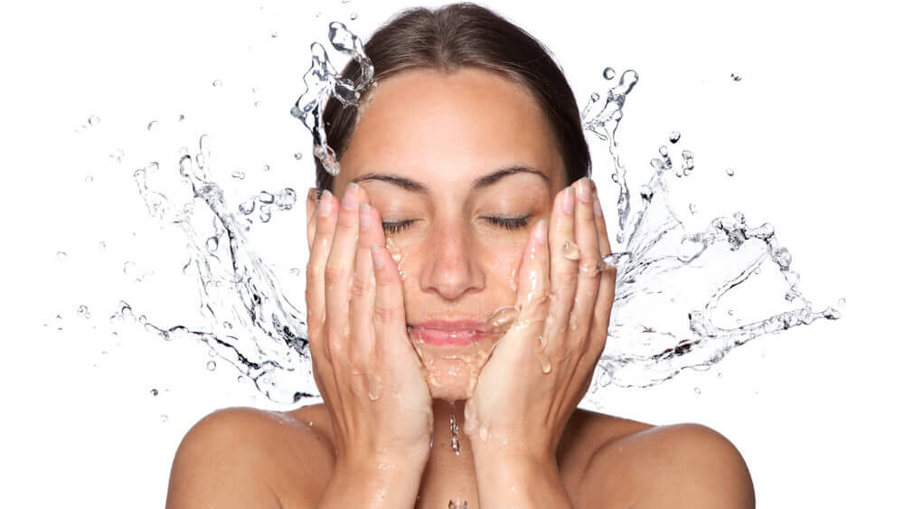 a woman is washing her face