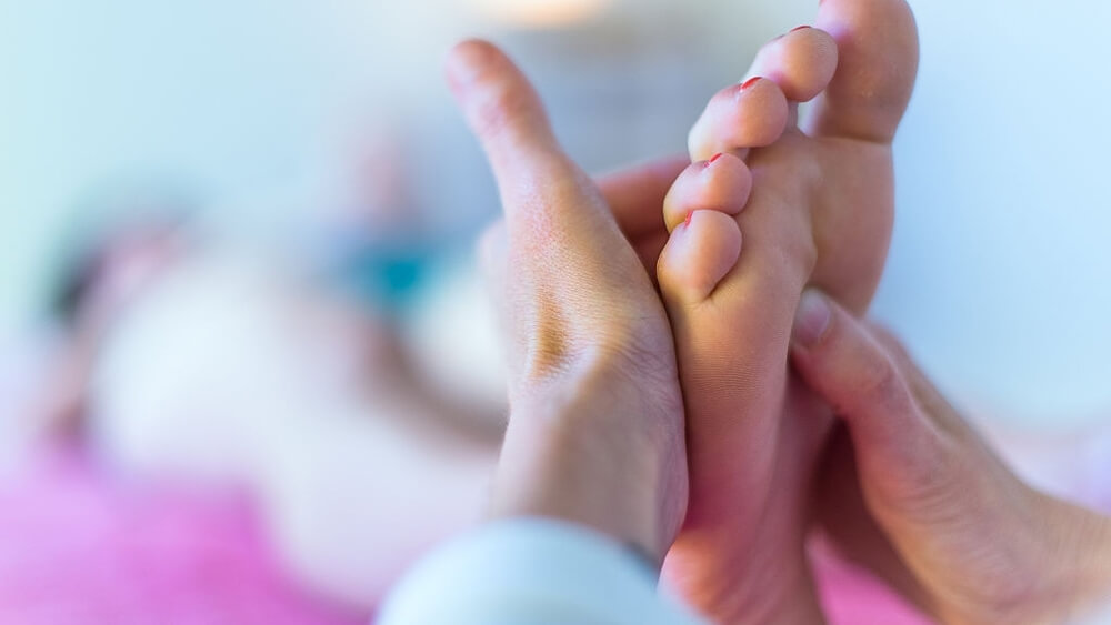 Therapists hands massaging female foot with acupressure