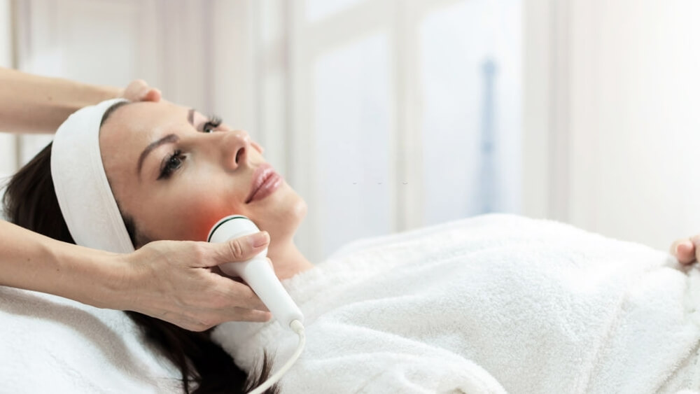 a woman has facial laser treatment in beauty spa